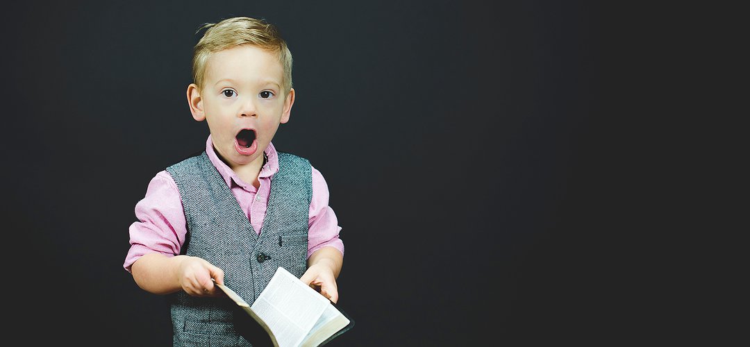 Un enfant tient un livre dans les mains. Il a l'air très étonné !