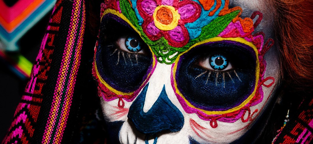 Un visage de femme maquillé de couleurs vives, façon dia de los muertos