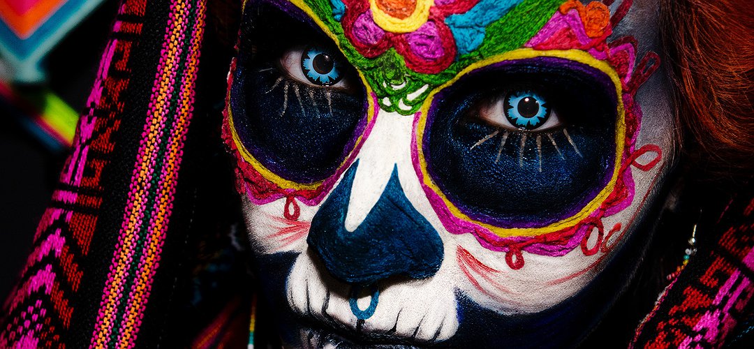 Un visage de femme maquillé de couleurs vives, façon dia de los muertos