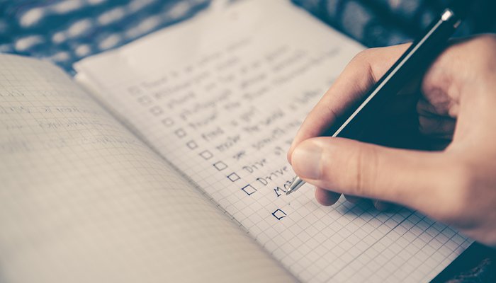 Une main tient un stylo au dessus d'une feuille de papier