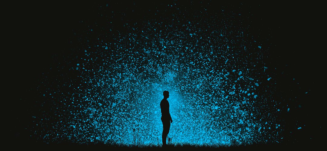 A man standing in pitch black with hundreds of tiny blue lights behind him