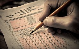 A hand holding a pencil above a test sheet