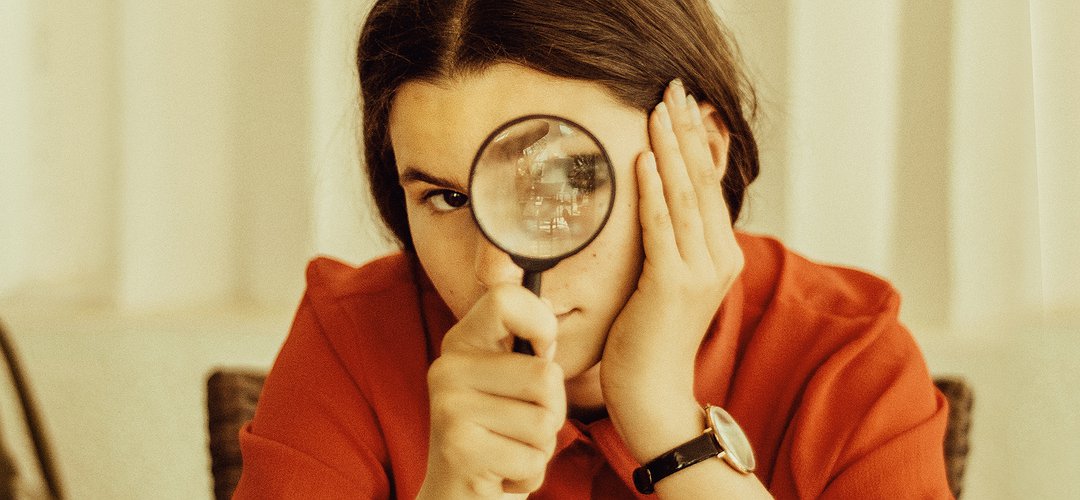 Une femme tient une loupe devant son oeil gauche
